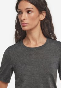 Mørkegrå strikket t-shirt med korte ærmer, rund halsudskæring og glat tekstur. Har et tætsiddende design og ensartet syninger.