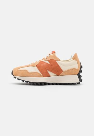 Beżowo-pomarańczowy zamszowy i materiałowy sneaker z czarną fakturowaną podeszwą i białymi sznurowadłami, widziany od zewnętrznej strony.