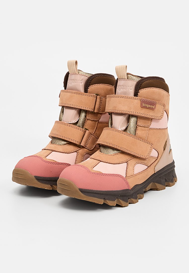 Tannfarbene und rosa Wanderschuhe mit Klettverschlüssen, aus Wildleder und Mesh-Materialien, mit strukturierten Sohlen und goldenen Akzenten, die für Stabilität und Grip entwickelt wurden.