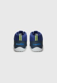 Marineblauwe sportschoenen met een textiel bovenwerk, met een twee-kleurig ontwerp en felgroene accenten op de achterkant en zijkanten.