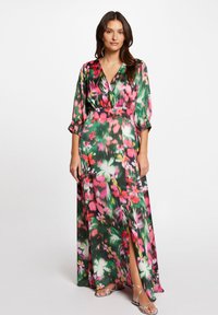 Abito lungo in satin verde con motivo floreale rosa e bianco. Presenta una scollatura a V profonda, maniche a tre quarti e uno spacco laterale.