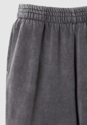 I pantaloni grigi in felpa hanno una texture morbida, una cintura elastica e tasche laterali. Il tessuto presenta un motivo a maglia uniforme.