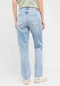 Jeans de denim azul claro con un corte recto, que cuentan con dos bolsillos traseros y una etiqueta de cuero marrón en la cintura.