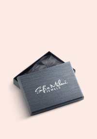 Grå texturerad smyckeslåda med ett något upphöjt lock, med "Sofia Milani JEWELS" i vit kursiv text, fodrad med svart silkespapper inuti.