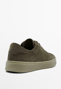 Groene suède sneakers met een laag model, een ronde neus en een dikke beige rubberen zool. De hiel heeft een subtiel gestikt accent.