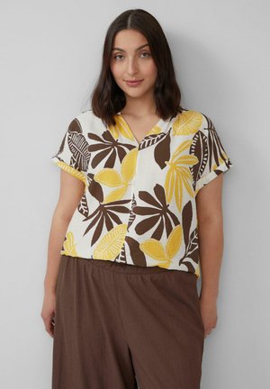 Korte mouwen blouse met een witte achtergrond en grote bruine en gele bladerenpatronen, V-hals ontwerp en een losse pasvorm.