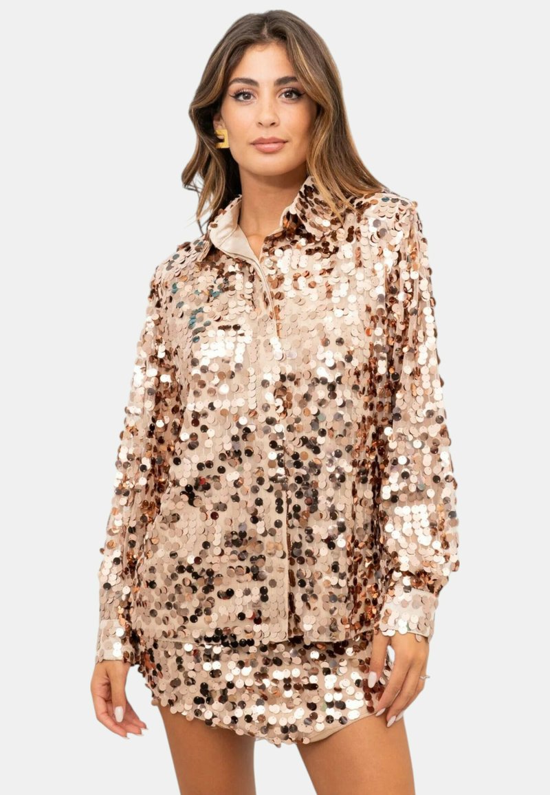 Top in lamè rosa con paillettes, con colletto, maniche lunghe e vestibilità rilassata. Presenta un mix di paillettes grandi e piccole per dare texture.