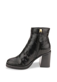 Botín negro hasta el tobillo con textura de reptiles, punta redondeada, cremallera lateral con herrajes dorados y un tacón grueso negro.
