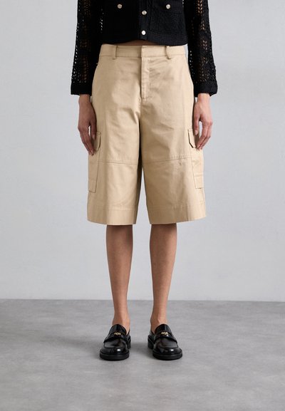 Pantaloni scurți cargo din bumbac bej, cu buzunare laterale, design până la genunchi și cusături vizibile. Purtați cu mocasini negri pentru contrast.