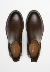 Bottes chevilles en cuir marron avec une finition lisse, des panneaux latéraux élastiques et une languette au talon. Présentent un bout arrondi et un branding subtil.