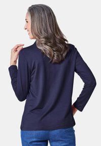 Marinefarbener Langarmtop aus weichem Stoff mit lockerer Passform und Rundhalsausschnitt. Glatte Textur mit einem schlichten Design.