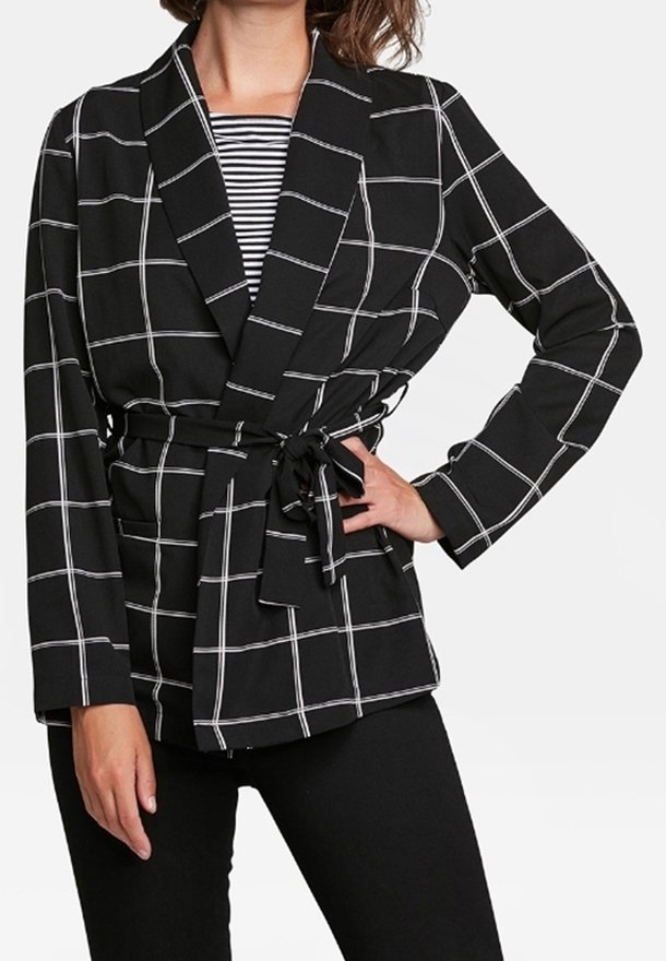 Svart kavaj med vit rutmönster, bälte i midjan, långa ärmar och sjalkrage, över en randig topp.