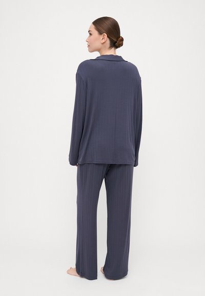 Dark blue ribbed pajama set, featuring a long-sleeve shirt and wide-leg pants. The fabric appears soft with a relaxed fit.