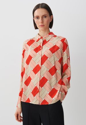Long-sleeve button-up shirt in silky fabric features a geometric red, pink, and beige pattern with a spread collar and cuffed sleeves.