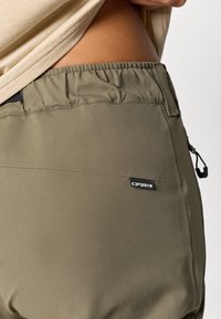 Ελαιόχρωμο παντελόνι με ελαστική μέση και απαλή υφή. Διαθέτει πλαϊνή τσέπη με φερμουάρ και μικρό μαύρο λογότυπο της μάρκας στο πίσω μέρος.