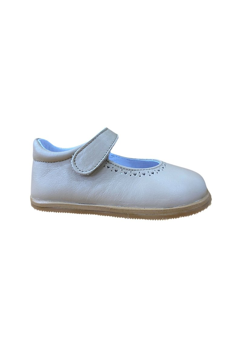 Zapato de cuero gris claro con puntera redonda, borde ondulado y correa ajustable. Presenta una suela de goma beige con tracción.