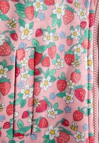 Rozā audums ar sarkaniem zemesriekstiem, baltām un zilām puķēm, zaļām lapām un dzelteni-melnām bitēm, labajā pusē ar rozā rāvējslēdzēju.