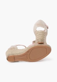 Sandale compensée avec un dessus en tressé de couleur beige clair et rose, talon texturé contrastant et semelle en caoutchouc avec un motif de bande de roulement unique.