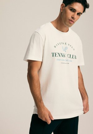 Biała bawełniana koszulka z nadrukiem "Tennis Club" w zielonym i niebieskim kolorze, krótki rękaw, okrągły dekolt, luźny krój i gładka faktura.