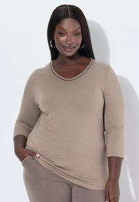 Beige dlouhý rukáv top s výstřihem do V a zdobeným límečkem. Hladká tkanina se jemně splývá, má jemný lesk a volný střih.