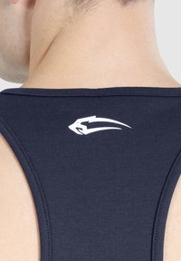 Granatowy top na ramiączkach o dopasowanym kroju, z białym logotypem przy dekolcie. Materiał wydaje się gładki i elastyczny.