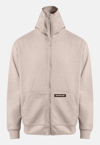Sweatshirt beige zippé avec col montant, deux poches latérales, poignets côtelés et ourlet, présentant une petite étiquette noire sur la poche gauche.