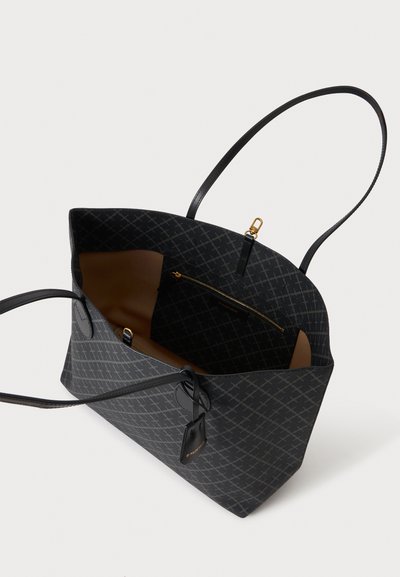 Sac cabas noir avec motif géométrique, deux fines poignées, poche intérieure zippée et petite étiquette suspendue sur fond blanc.