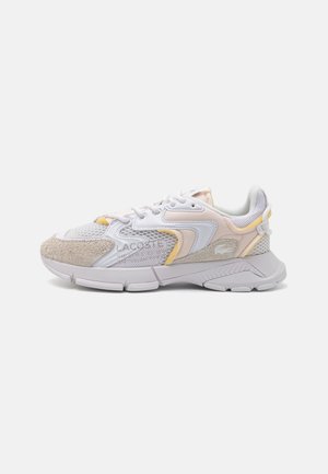 Sneaker bianco da atleta con accenti in rete e suede, caratterizzato da una suola imbottita, morbidi dettagli gialli e un design testurizzato sul lato.