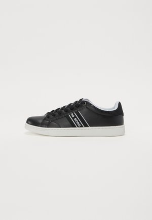 Black sneaker with white sole, featuring a smooth leather upper, round toe, black laces, and white accents running along the sides.