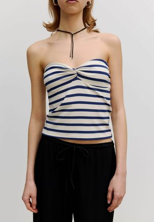 Strapless ribbeltop met marineblauwe en witte horizontale strepen, voorzien van een twistdetail in het midden. Draagt met zwarte broek met trekkoord.
