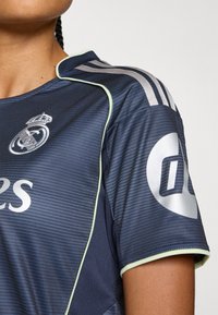 Navy blue sports jersey with a ribbed texture, silver accent stripes, and a light green trim. Features a logo and number on the sleeve.