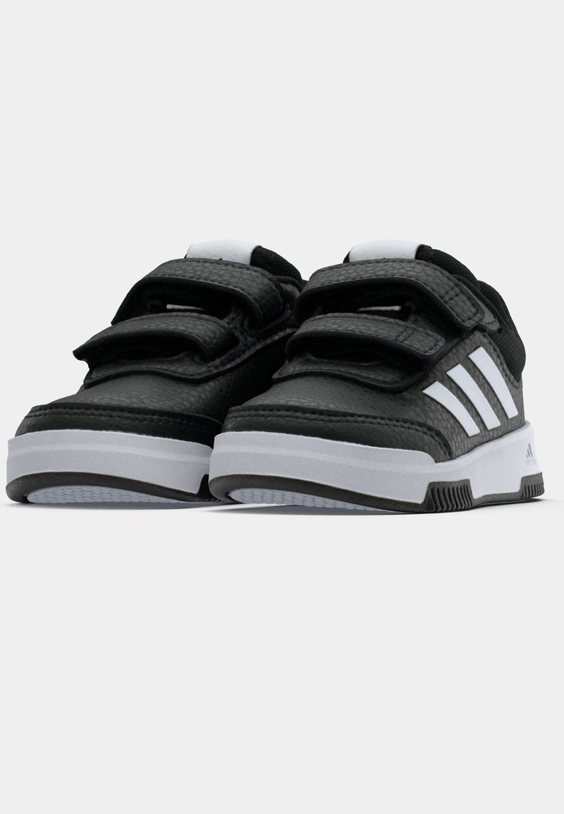 Schwarz-weiße Adidas Sneaker mit doppelten Velcro-Riemen und weißer Sohle, von vorne auf einem weißen Hintergrund betrachtet.