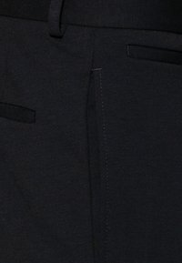Black fabric pants, featuring a smooth texture, with side pockets and a clean seam design. No visible patterns or hardware details.