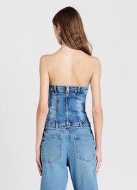 Top corsetto in denim azzurro chiaro, design senza spalline con una forma strutturata, dotato di chiusura con cerniera e dettagli di cuciture visibili.