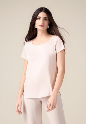 Top corto a maniche corte di colore rosa chiaro con scollatura arrotondata, realizzato in un tessuto morbido e liscio. Presenta un fit rilassato e spacchi laterali all'orlo.
