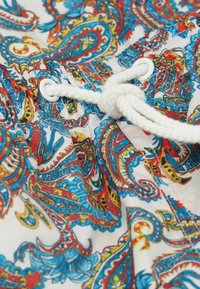 Tela con estampado de paisley multicolor con acentos en azul, rojo y amarillo; presenta un cordón blanco y un detalle de cintura fruncida.