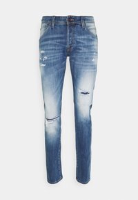 Siniset farkut haalistuneella pesulla, kapea malli ja useita kulutettuja kohtia. Mukana viisi taskua ja vyölenkillinen vyötärö.