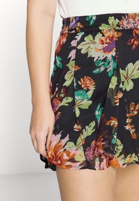 Floral skirt in black fabric with vibrant green, orange, and pink floral patterns. Features a pleated design and an elastic waistband.