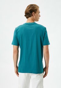 Teal bomulds T-shirt med korte ærmer, rund halsudskæring og lige snit, med en glat tekstur og minimalistisk design.