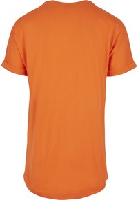 Tricou scurt cu mâneci scurte de culoare portocalie, cu decolteu rotund, fabricat din bumbac. Prezintă mâneci răsucite și un tiv ușor curbat în partea de jos.