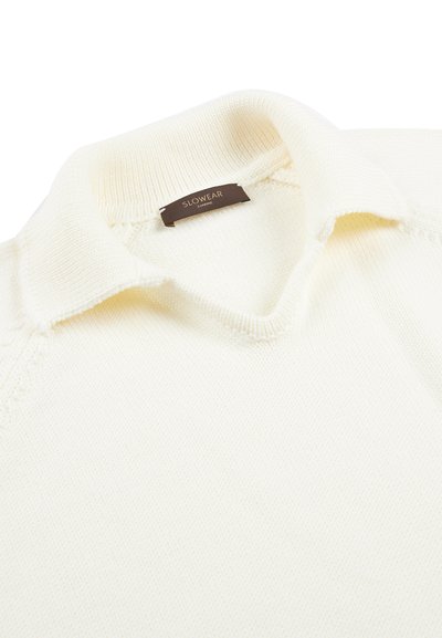 Maglione lavorato a maglia color crema con colletto a coste e un'etichetta marrone che riporta la scritta "SLOWEAR ZANONE" all'interno dello scollo.