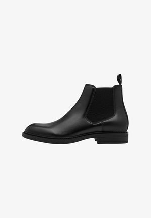 Bota Chelsea de cuero negro con paneles elásticos en los lados, una lengüeta y una suela plana con un sutil detalle de costura. Textura suave en toda la superficie.