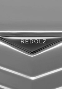 Silberne Reisetasche mit einer schlanken, strukturierten Oberfläche; verfügt über einen schwarzen dreieckigen Akzent mit dem eingeprägten "REDOLZ" in Weiß.