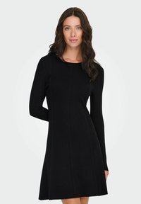 Schwarzes, geripptes Strickkleid mit langen Ärmeln, rundem Halsausschnitt und A-Linien-Silhouette, das vertikale Nähte für zusätzliche Textur aufweist.