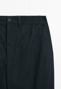 Dark navy trousers with elastic waistband, button closure, belt loops, and side pockets on white background.