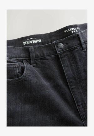 Mustad lõdvaltistuvad teksad, esiosas nööbiga ja vööaasadega, vöökohal sildiga "Next Denim Supply" ja suurusega "34R".