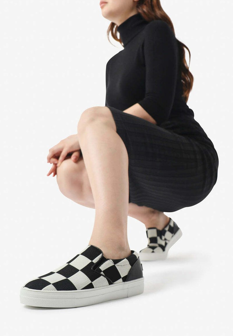 Sneakers slip-on a scacchi bianco e nero con suola in gomma, pannelli elastici laterali e una parte superiore in tessuto liscio dal design basso.