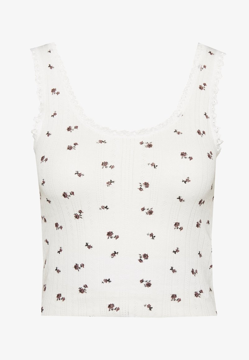 Top in cotone bianco con un motivo testurizzato, caratterizzato da piccoli motivi floreali in rosa e marrone. Bordo in pizzo smerlato lungo il colletto e le maniche.