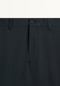 Mörkblå byxor med slät fram, bältesögglor, knappstängning och en subtil textur. Enfaldig design utan synliga mönster eller detaljer.