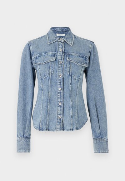 Lys blå denimskjorte med skjortekrage, lange ermer, to brystlommer og knappelukk. Har synlige stikninger og buet kant.